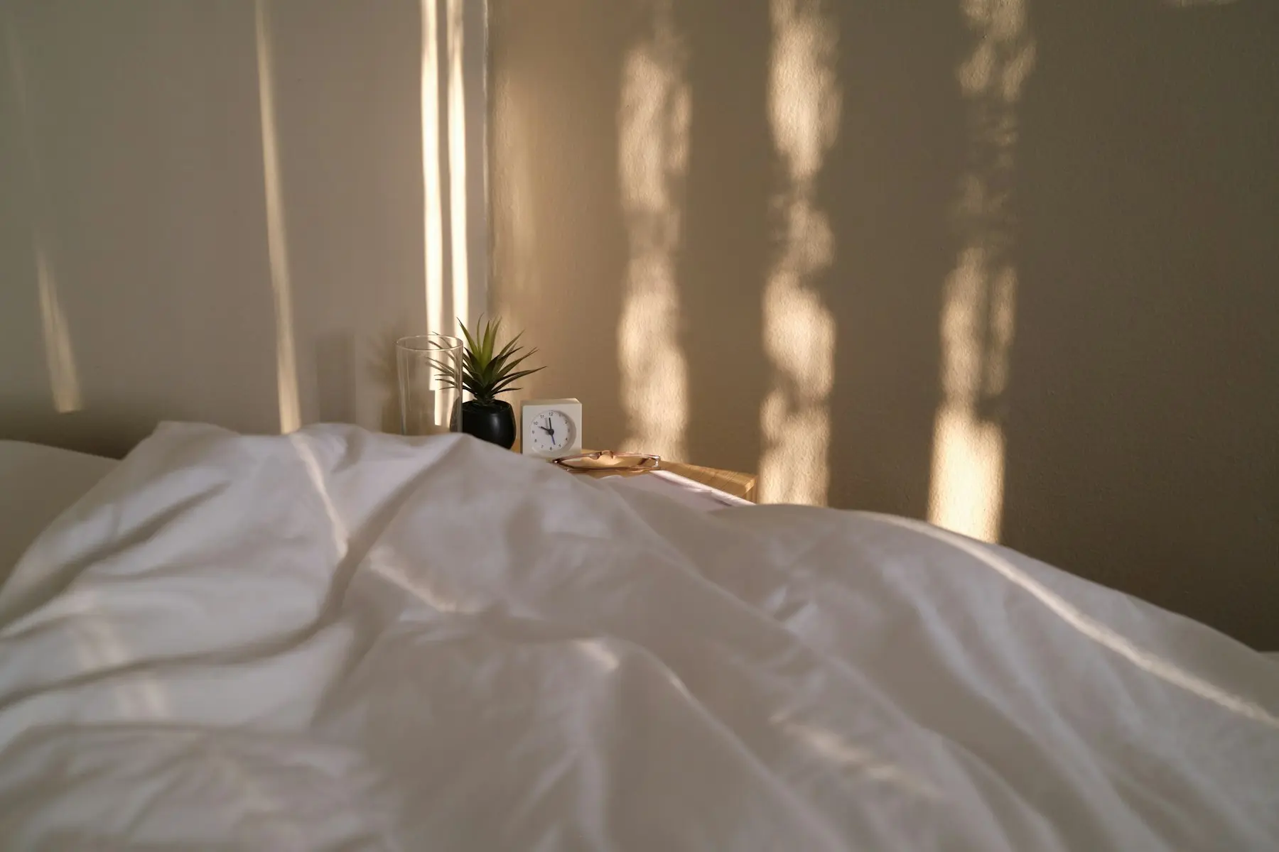 Late afternoon light falling across the bed through window blinds