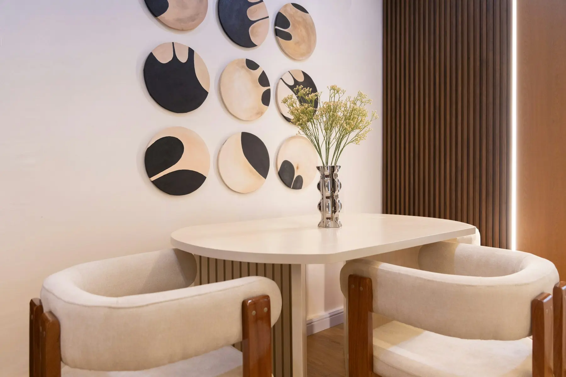 The dining nook with upholstered chairs and abstract art on the wall behind