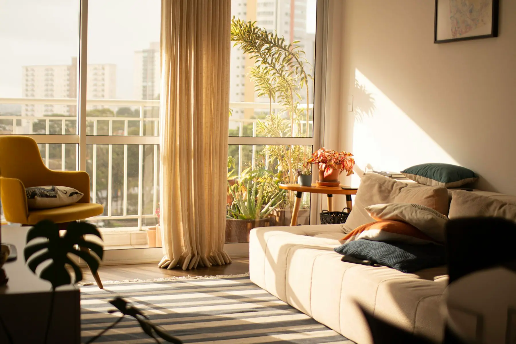 The sitting room at Lachica Homes in Kyanja, Kampala — a low sofa, warm curtains and the balcony door open to morning light