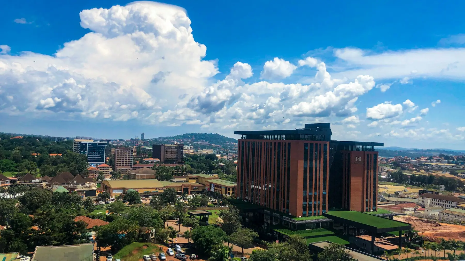 A wide view over Kampala's green hills and rooftops, looking towards the city from the north