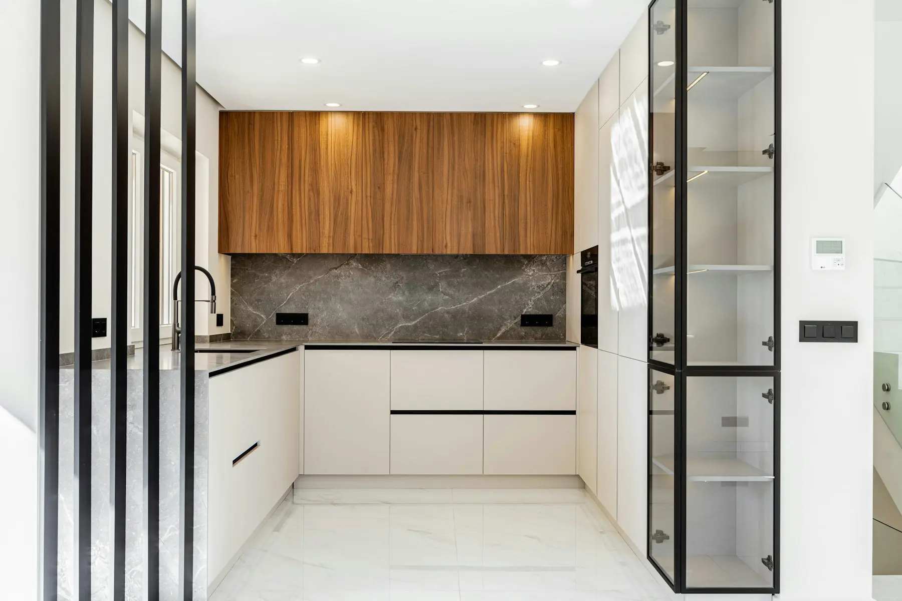 The kitchen with timber and white cabinets, a marble splashback and a window above the sink