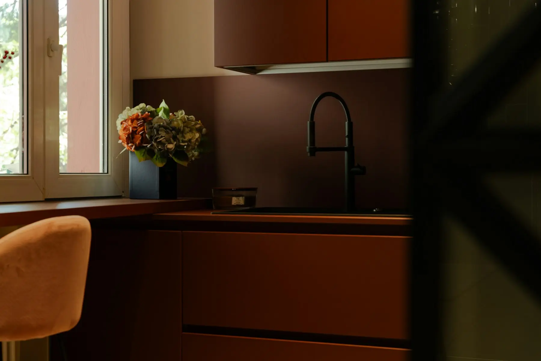 The kitchen counter in the late afternoon, with flowers in a vase beside the window